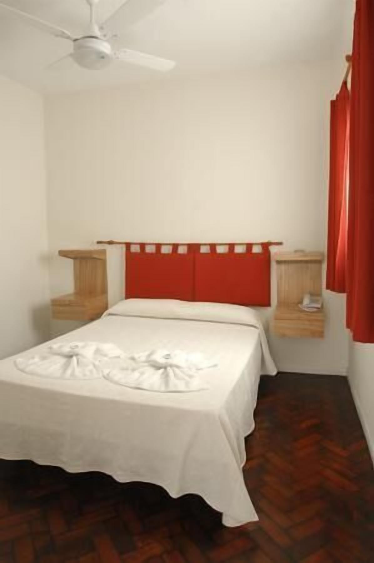 A small, clean room with a single bed, a nightstand, a red headboard, and a ceiling fan. - Hotel Patio del Mar (Mar del Plata)