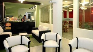 A hotel lobby with a reception desk, seating area with white chairs, and a view of the interior through large windows. - Hotel Patio del Mar (Mar del Plata)