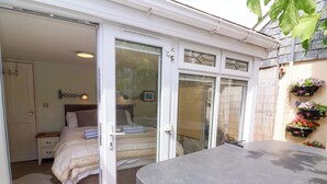 A bedroom with a bed, a nightstand, and a window with a view of the outside. - Sea Sanctuary (Bideford)