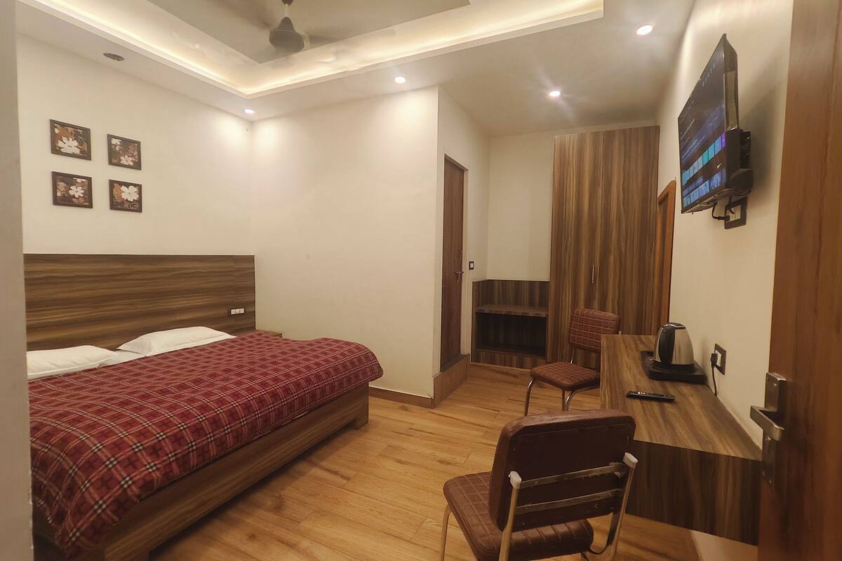 Un dormitorio con cama, escritorio, silla, televisor y armario.