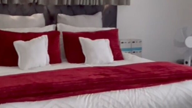 Un lit avec une couette rouge et blanche, une tête de lit grise et des oreillers rouge et blanc.