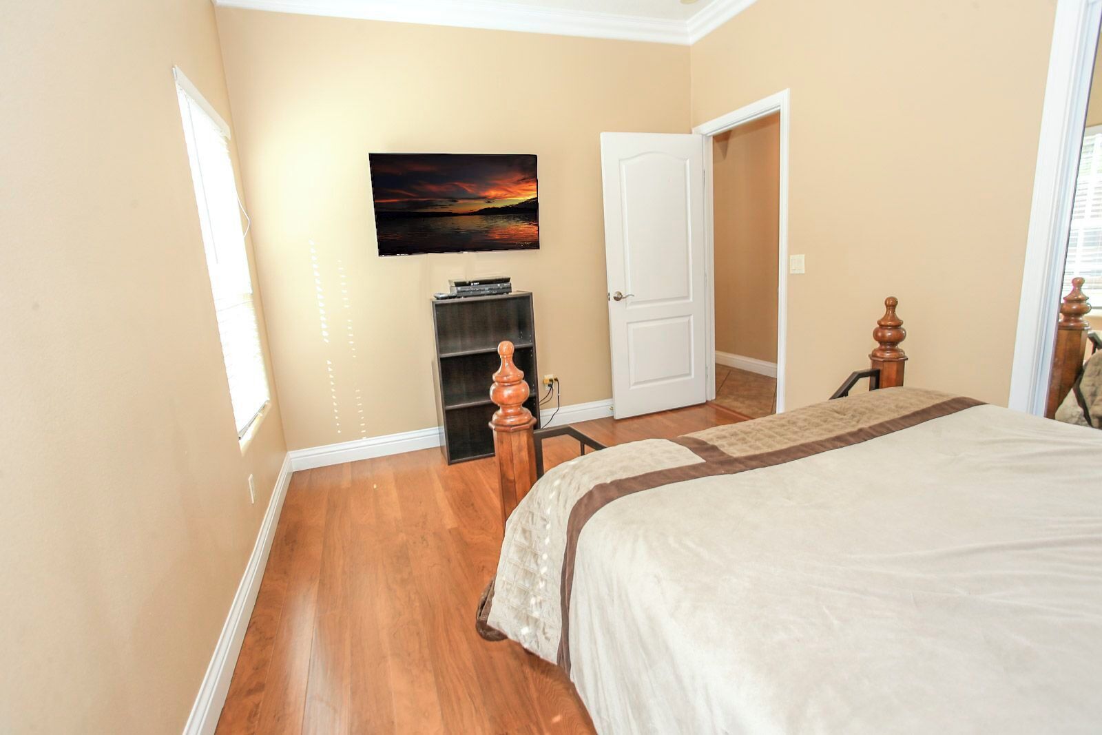 A bedroom with a bed, a painting, a door, and a small table.