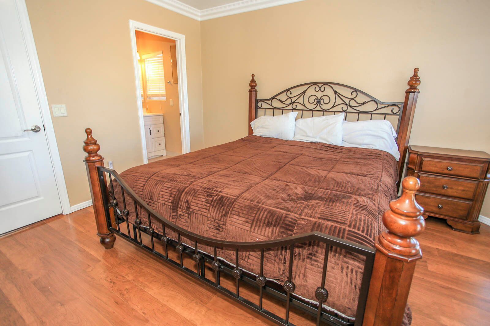 Une chambre à coucher avec un lit en bois, une couverture marron et une table de chevet dotée de tiroirs.