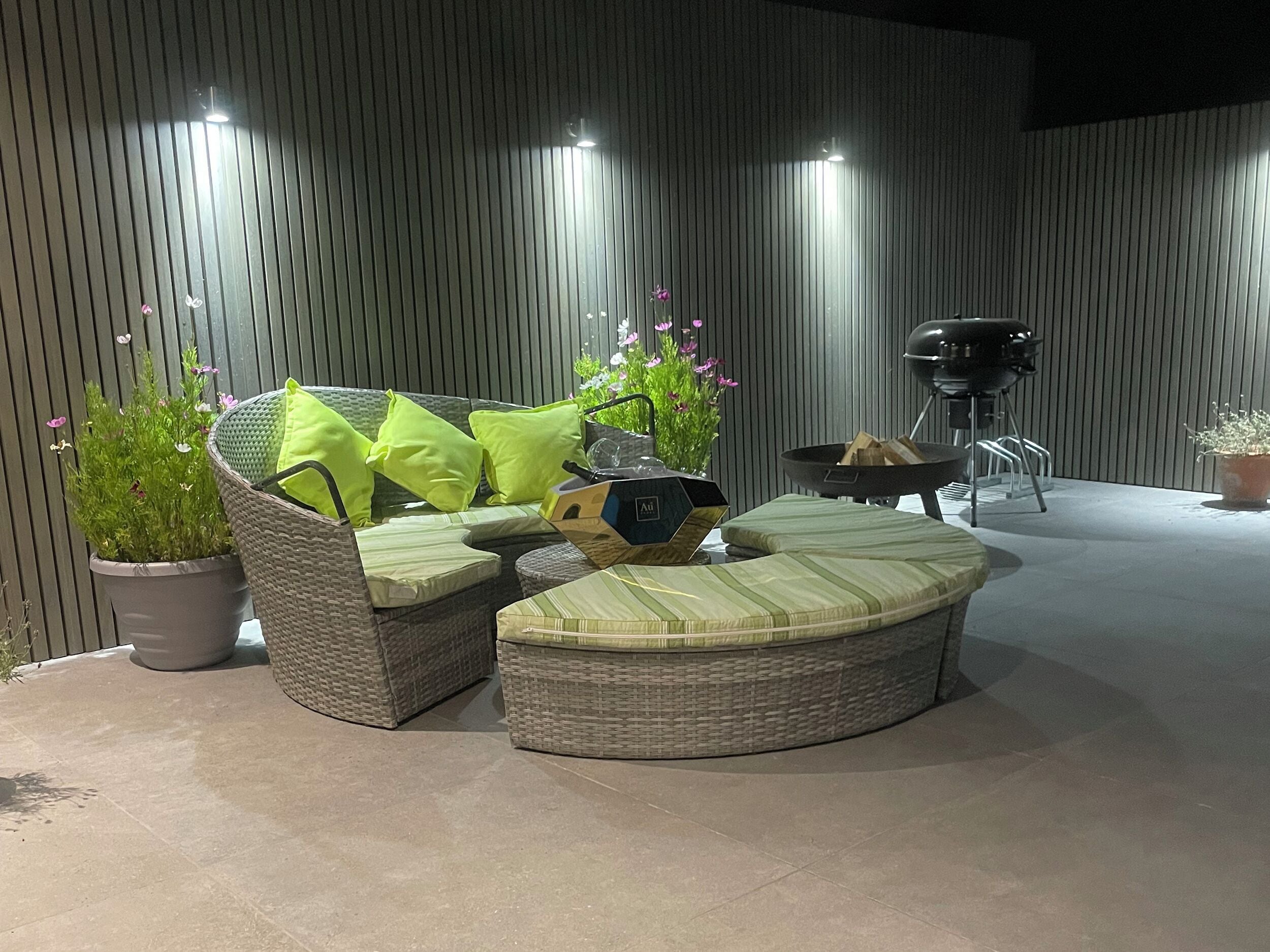 An outdoor seating area with wicker furniture, cushions, and a barbecue grill.