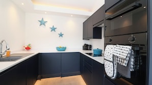 A modern kitchen with dark cabinets, a white countertop, a sink, and a stove. There are three blue star decorations on the wall.