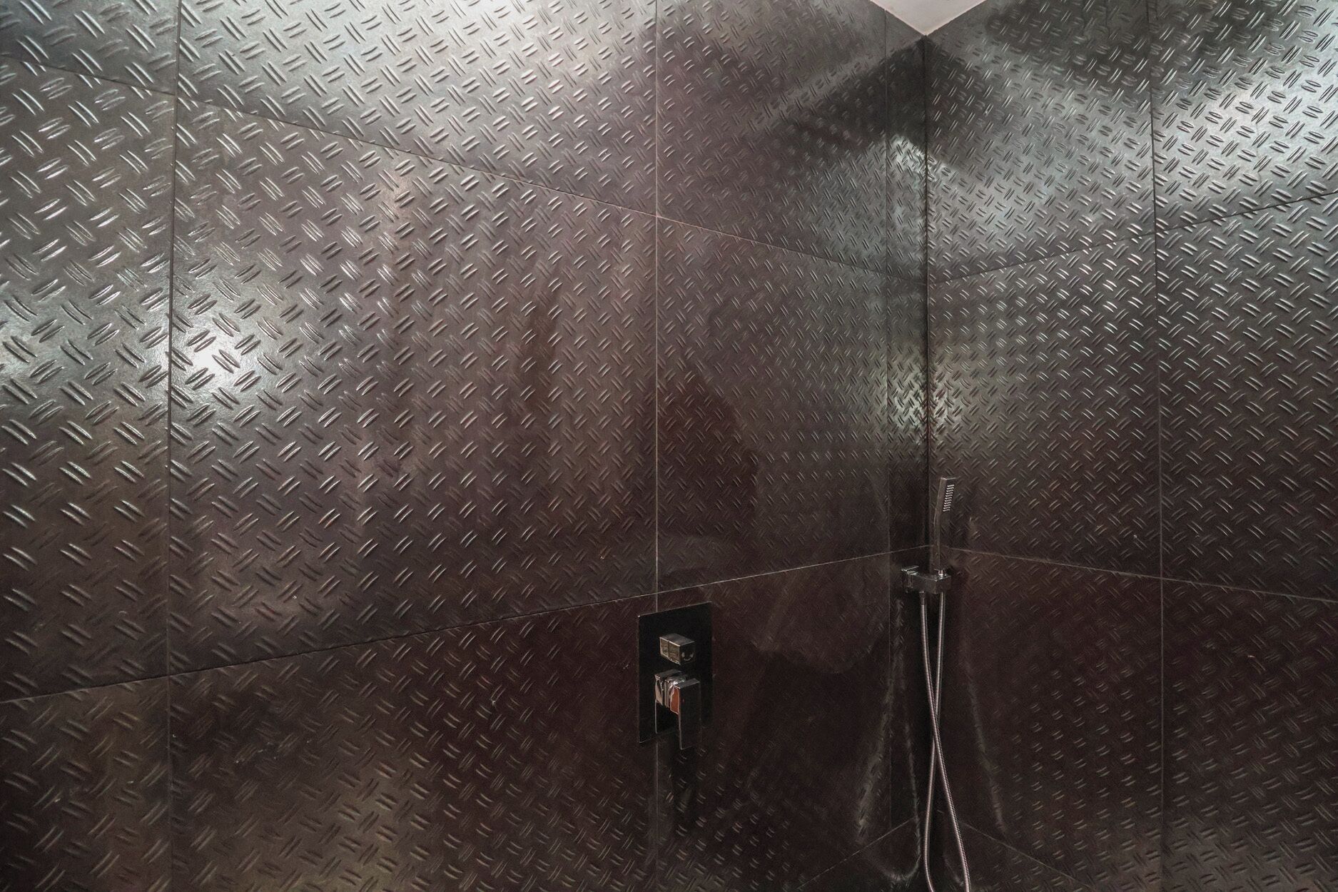 Eine Dusche mit Wandverkleidung aus gebürstetem Metall und einer Bedienkonsole.