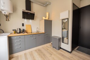 Een koelkast, een oven, een vaatwasser, kookgerei, borden en bestek