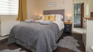 Hotellihuone, jossa on suuri sänky, yöpöytä lampun kanssa, peili ja näkymä kylpyhuoneeseen.