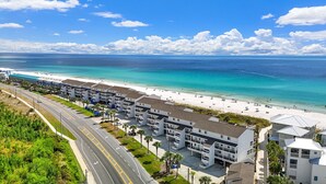 Un hôtel situé sur la côte, composé de plusieurs bâtiments à étages, avec une plage et une route menant à la plage.