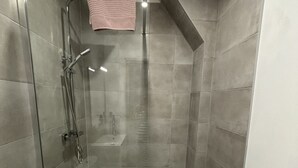 A walk-in shower with a glass door, a handheld showerhead, and a handheld showerhead with a hose. - Apartment in Ecommoy Near Le Mans Circuit (Ecommoy)