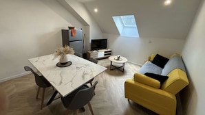 A compact living space with a dining table, sofa, and a small TV area. - Apartment in Ecommoy Near Le Mans Circuit (Ecommoy)