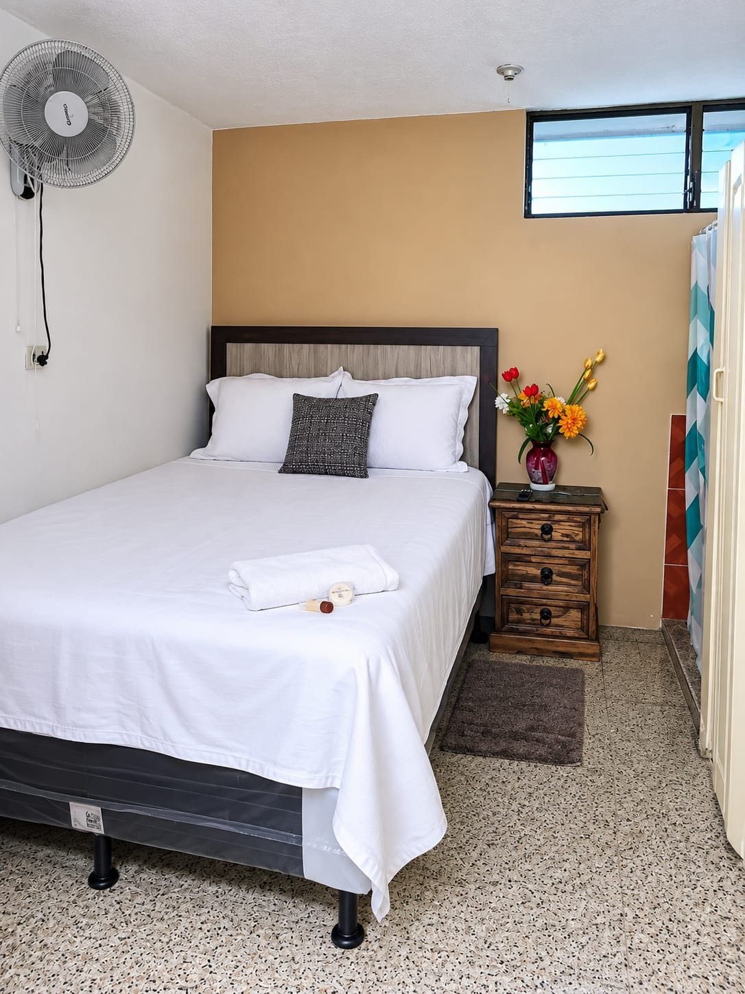 Quarto de hotel com cama, mesa de cabeceira e janela.