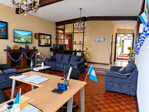 A living room with a sofa, a TV, a fireplace, and a chandelier. - EL TEJAR HOSTAL  (Guatemala City)