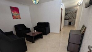 A living room with two black sofas, a coffee table, and a painting on the wall. - Beachfront Studios for couples, digital nomads, and surfers  in Tamraght, Aourir (awrir)
