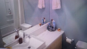 A bathroom with a sink, mirror, and toilet. There are two towels hanging on the wall.