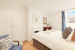 A bedroom with a bed, a dresser, a chair, a wardrobe, and a window with curtains. - No.20 - North East Escapes (Amble)