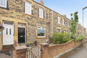 A stone-built terraced house with a white door, a black door, and a number '20' on the door. There are potted plants and a small garden area. - No.20 - North East Escapes (Amble)