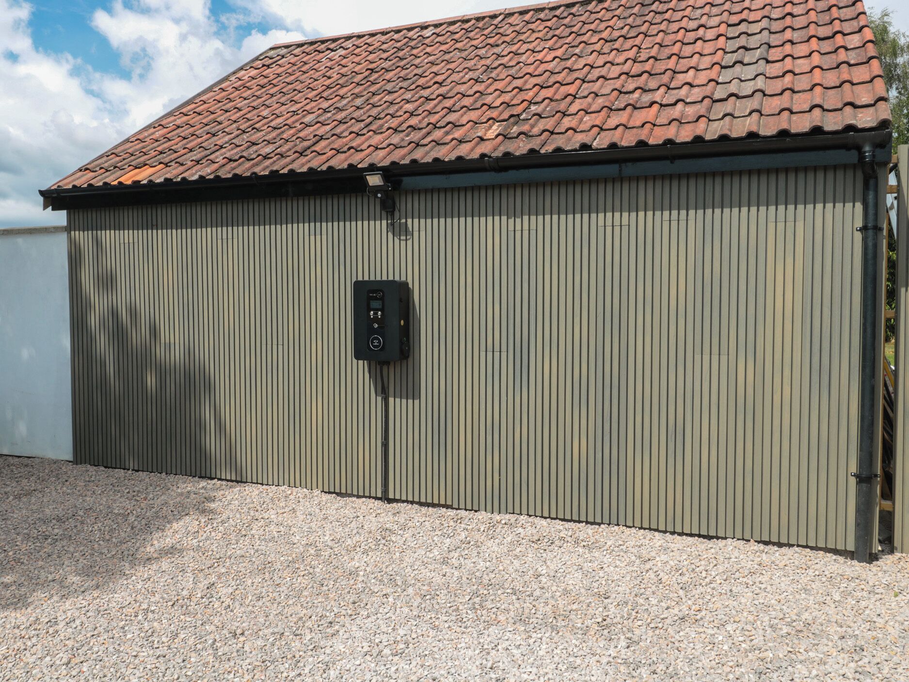 En stor, envåningsbyggnad med en fasad av korrugerad metall och ett rött tegeltak.