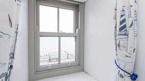 A corner room with a large window, white walls, and a view of the sea. - Shelstone (Whitby)