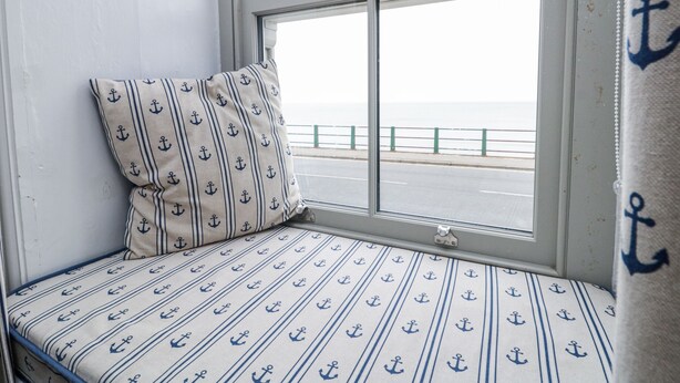 A window seat with a patterned cushion and a view of the sea. - Shelstone (Whitby)