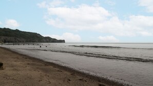 A beach with a sandy shore and a pier extending into the water. - Shelstone (Whitby)
