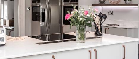 A modern kitchen with a stainless steel refrigerator, a built-in oven, and a white countertop.