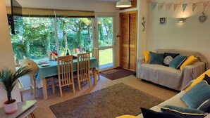 Una sala de estar acogedora con un sofá y una mesa de comedor preparada para dos.