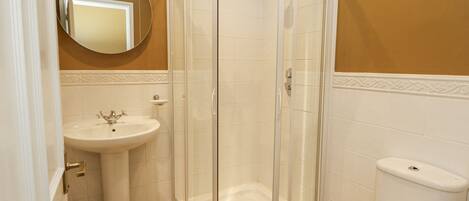 A bathroom with a glass-enclosed shower, a pedestal sink, and a toilet.
