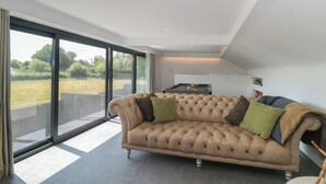 Un salon moderne avec une grande fenêtre, un canapé beige et une table de billard.