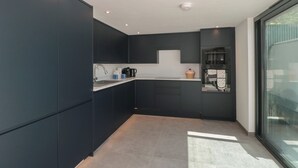 Une cuisine moderne avec des meubles de couleur sombre, un plan de travail et une fenêtre.
