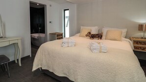Une chambre à coucher avec un grand lit, une table de chevet, une commode, un bureau et une chaise.