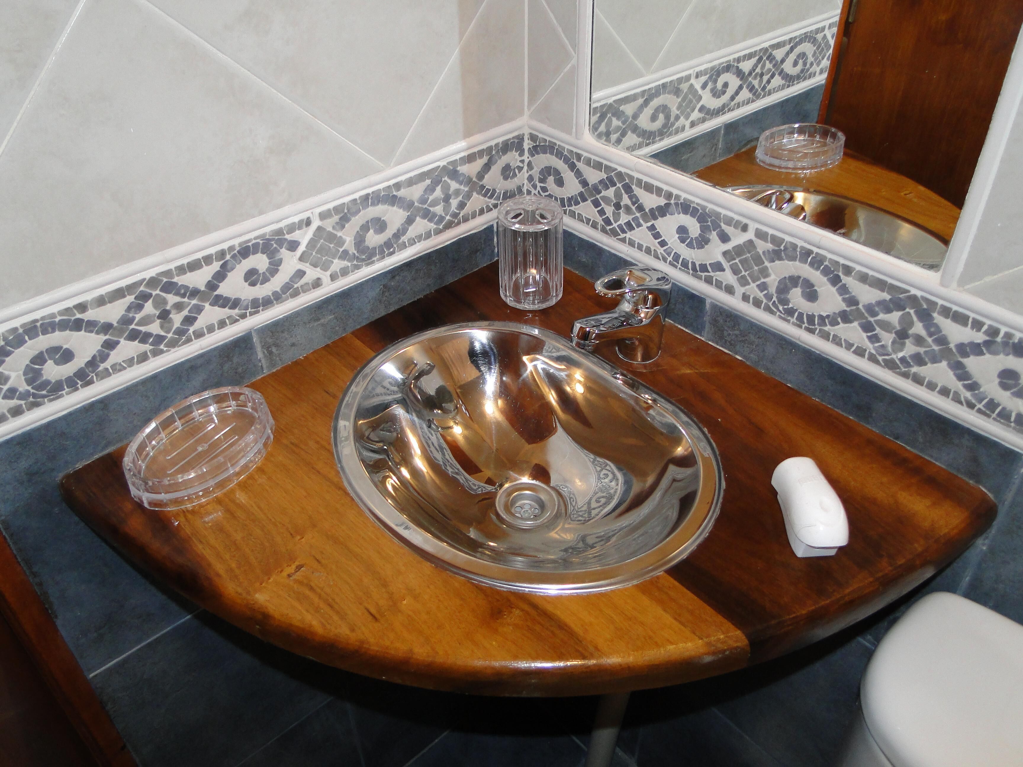 A bathroom with a wooden vanity, a sink with a faucet, and a mirror.