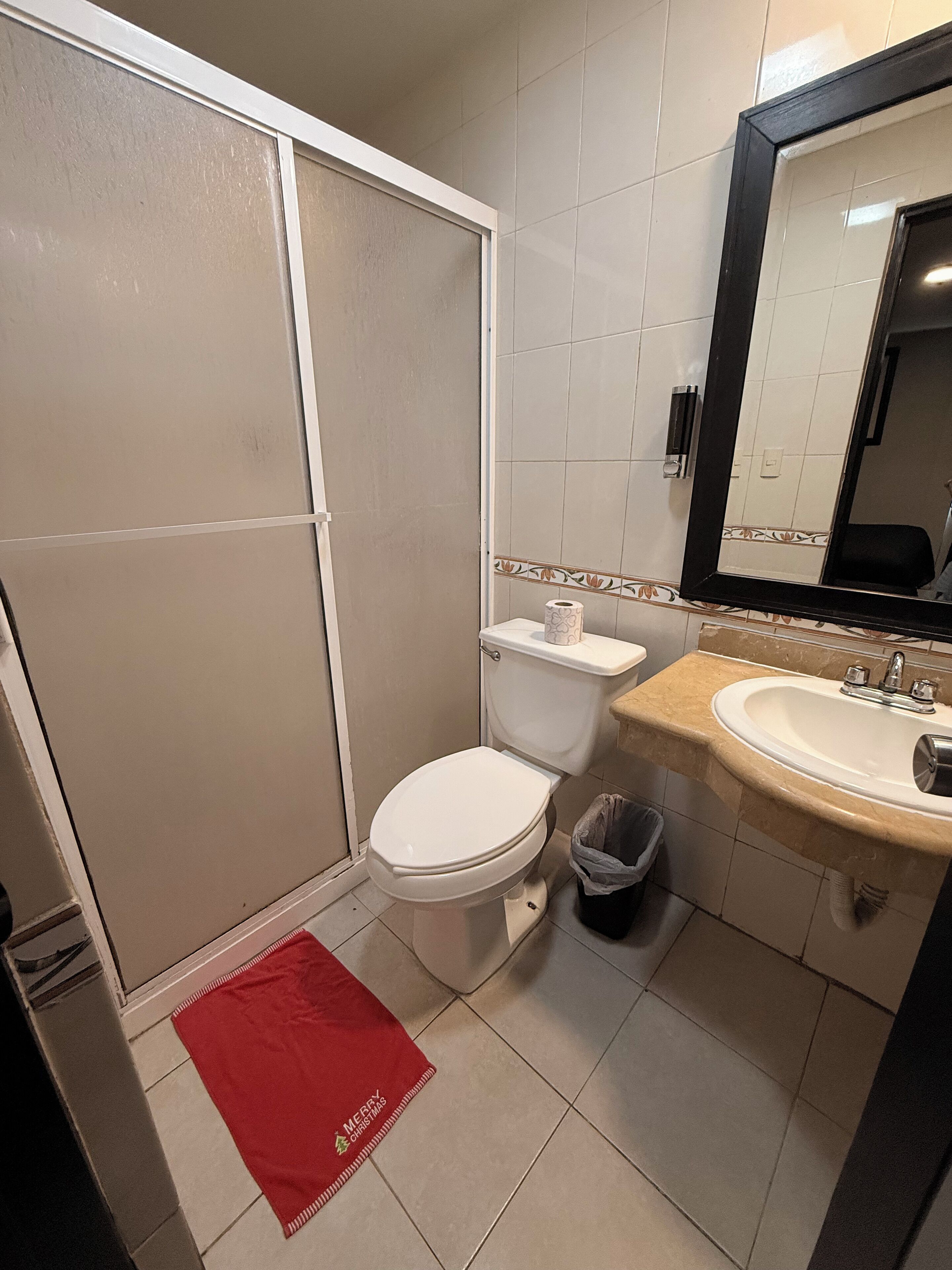 Un baño con inodoro, lavamanos y zona de ducha.