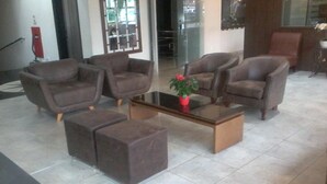 Uma sala de estar moderna com quatro poltronas, uma mesa de centro de vidro e um vaso com planta.