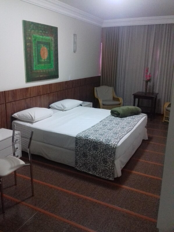 A hotel room with a bed, a chair, a small table, and a painting on the wall. - Hotel Rio do Sono (Palmas)