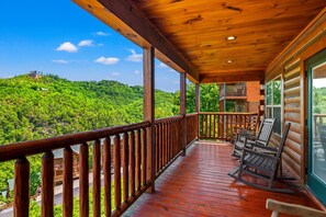 A wooden deck with a view of a forested hillside.