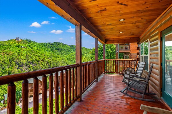 A wooden deck with a view of a forested hillside.