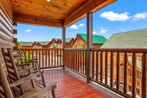 A wooden cabin with a porch, a bench, and a view of other cabins.