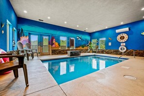 A swimming pool with a mural of ocean life on the walls, a clock, and a lifebuoy.