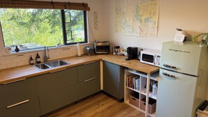 Une cuisine équipée d’un plan de travail en bois, d’un évier, d’un grille-pain, d’une machine à café et d’un réfrigérateur.