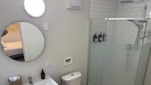 Une salle de bain avec un lavabo blanc, des toilettes et une douche à parois de verre.