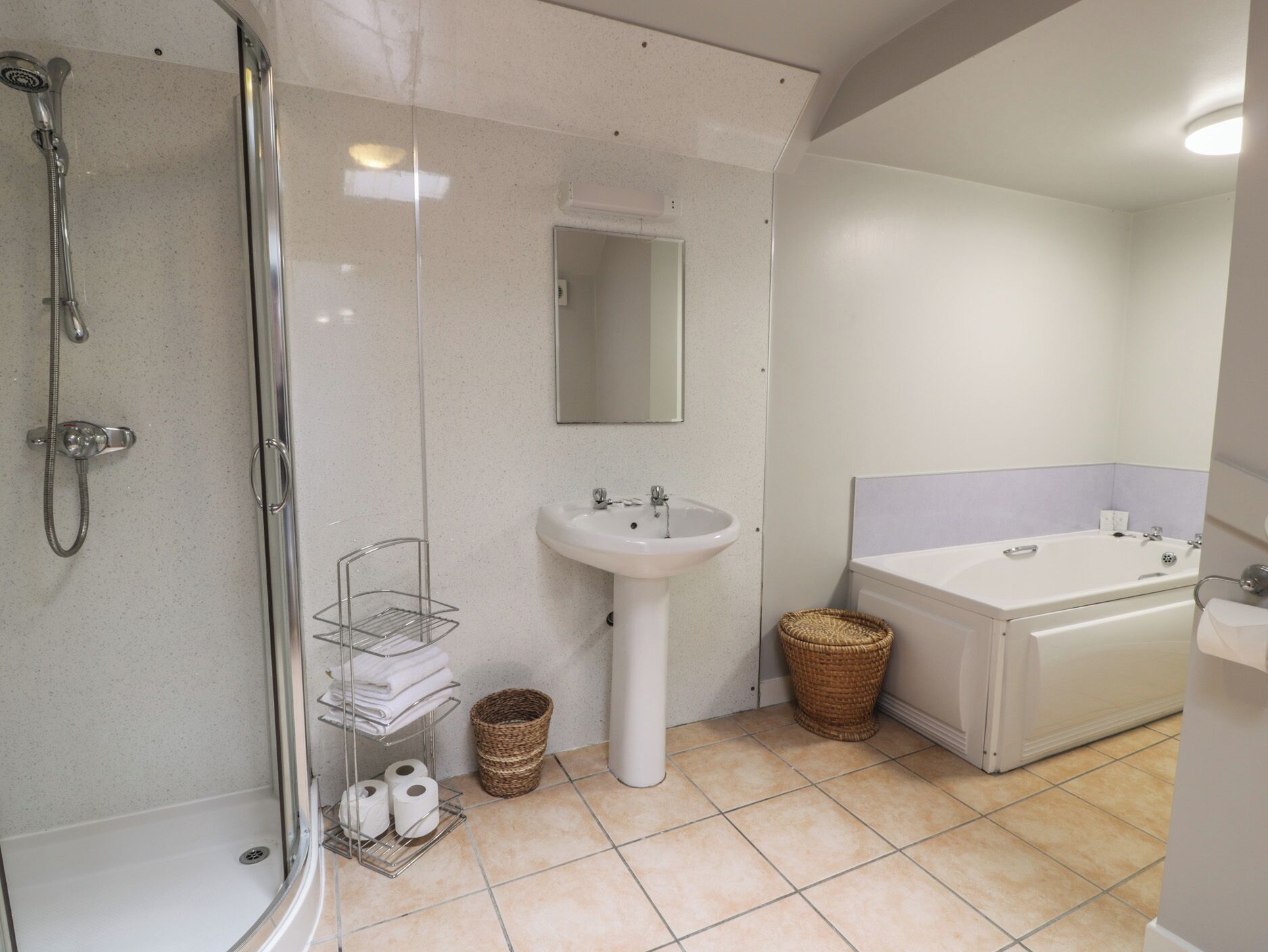 A modern bathroom with a glass-enclosed shower, a pedestal sink, a large bathtub, and a mirror above the sink.