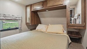 Un dormitorio con cama, ventana con vistas y muebles de madera sobre la cama.