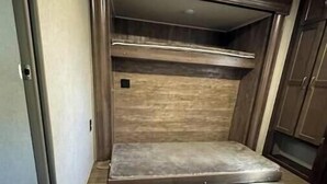 Una habitación compacta con cama integrada, piso de madera y armario.