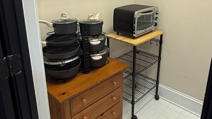 Een kleine keuken met een magnetron, een tafeltje en een houten kastje.