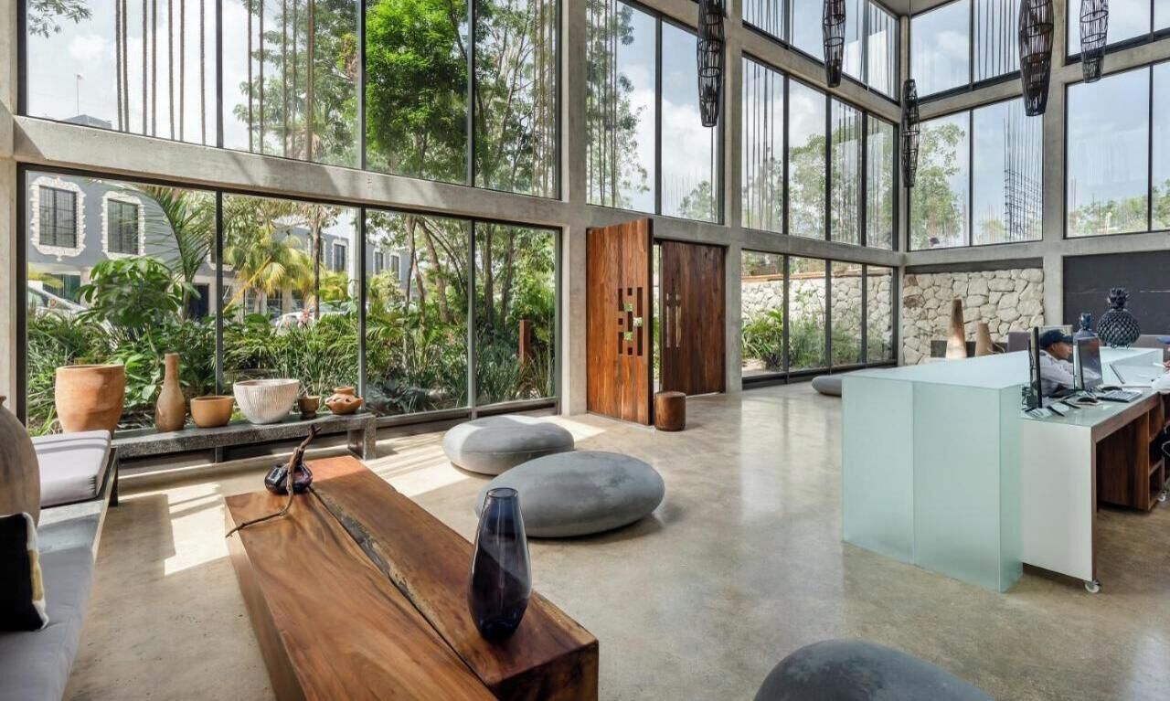 A spacious room with a large glass wall, a wooden desk, and a comfortable seating area.