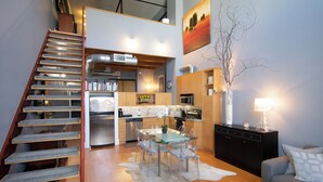 Une cuisine moderne avec un coin repas, un escalier et un salon comprenant un canapé et une lampe.