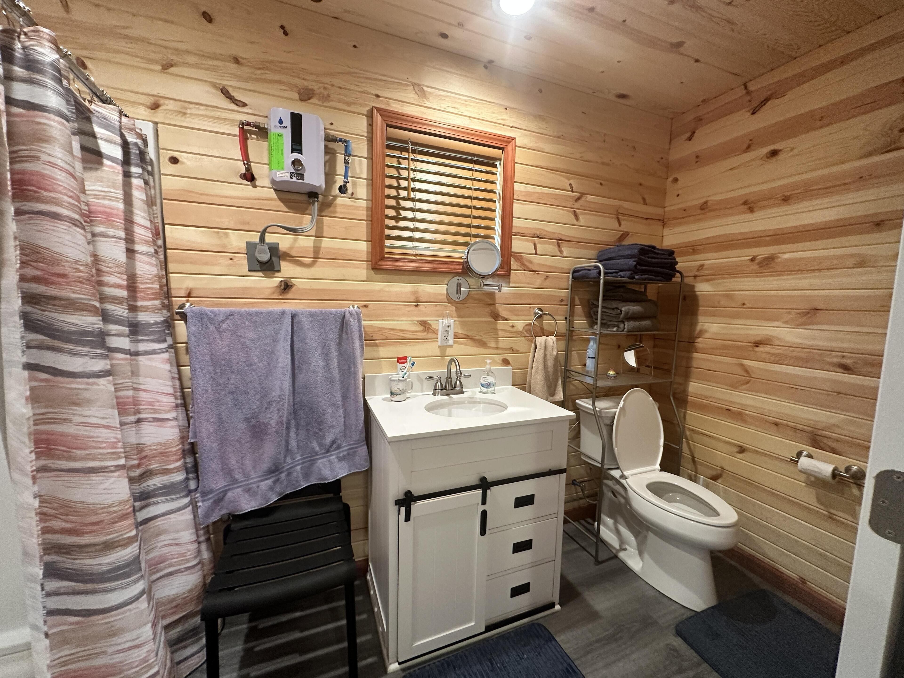 Een badkamer met houten lambrisering, een wastafel, toilet en douchegordijn.