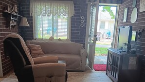 Un salon avec un canapé, un fauteuil et un téléviseur posé sur un meuble.