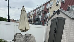 Un espace patio doté d’un sol carrelé en forme d’hexagone, d’une petite table avec des chaises et d’un parasol.